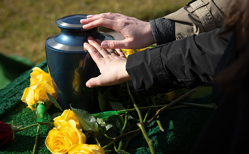 hand on casket with yellow roses