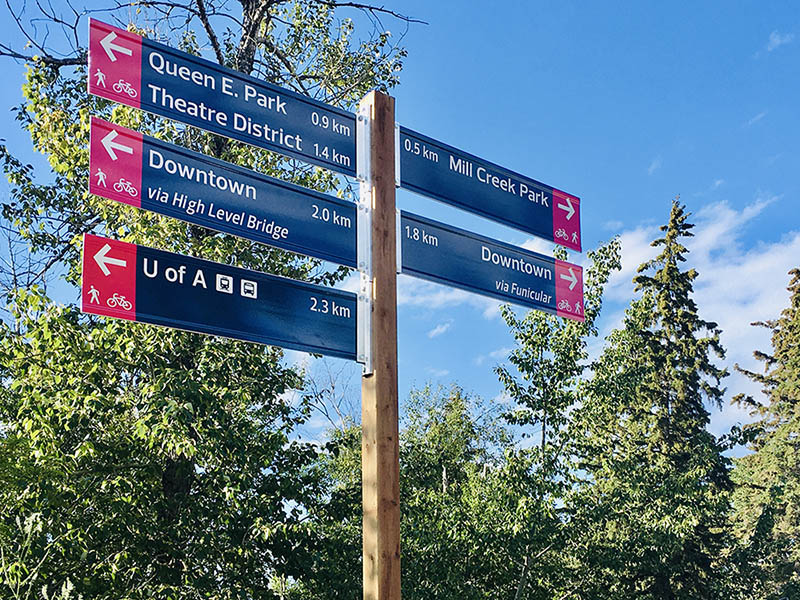 A bike wayfinding sign with distances and directions to several destinations in Edmonton