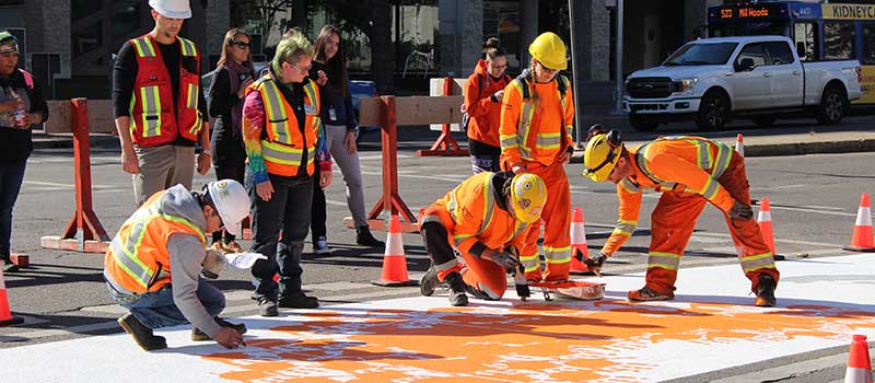 Workers and volunteers painting an Every Child Matters crosswalk