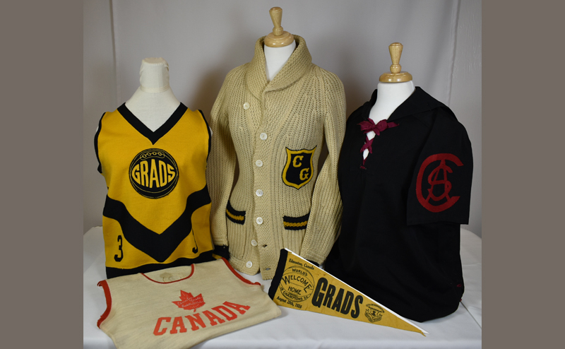 Various Grads uniforms and a flag on display.