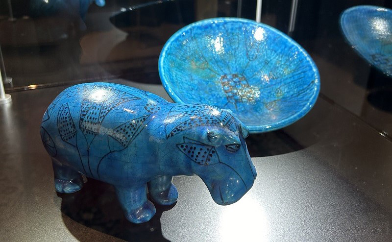 A blue bowl and hippo sculpture on display.