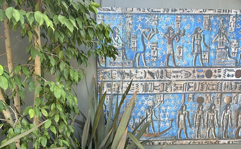 Ancient Egypt-themed artwork on display next to a tree.