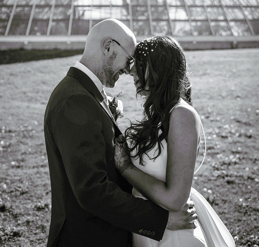 Black & white photo of bride and groom outside and in front of pyramid