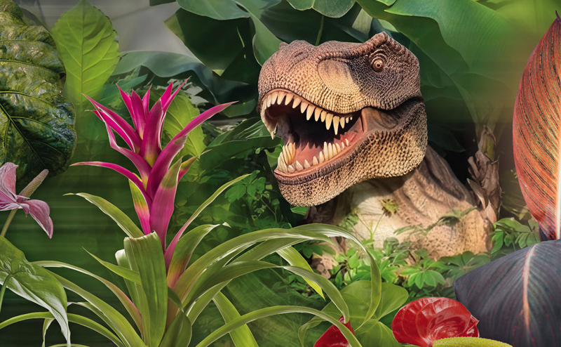 A T-Rex sculpture next to a green and pink plant.