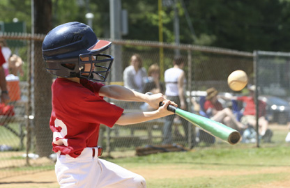 Young child swinging a bat at a baseball game