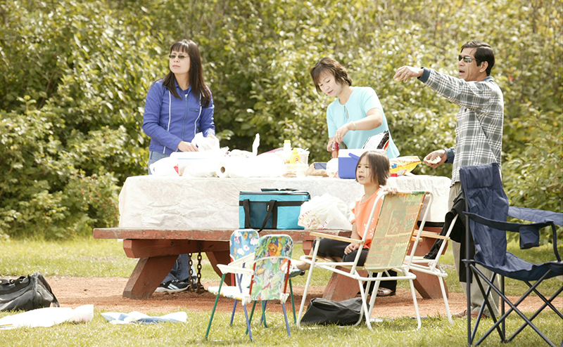 A family using a picnic bench in a park.