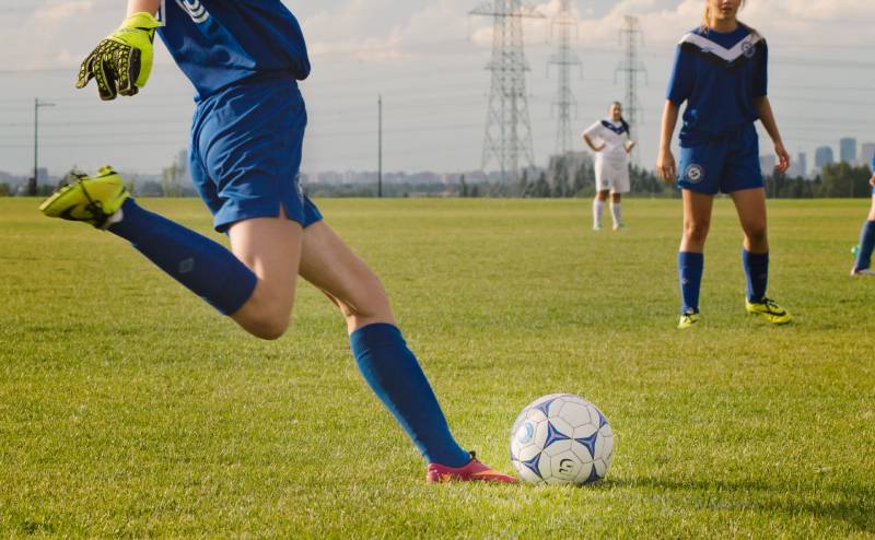 Person kicking a soccer ball on a sports field