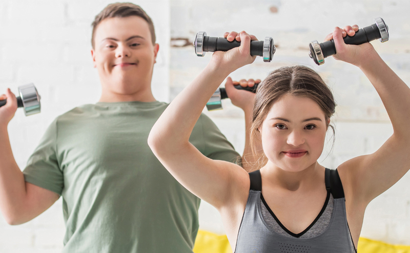 A man and woman with disabilities lifting dumbbells.