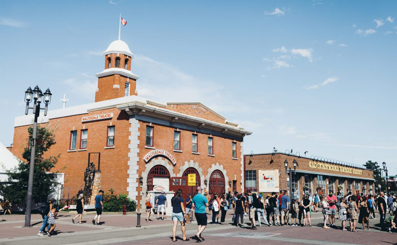 pedestrians on street in front of farmers market building