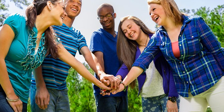 diverse teens joining hands in the centre of a circle