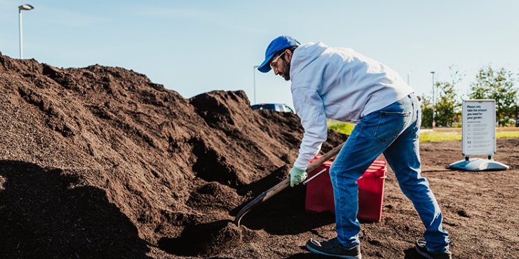 person with shovel collecting compost