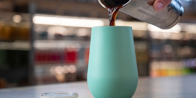 person pouring coffee into reusable cup