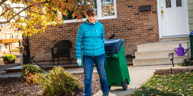 woman wheeling food cart bin