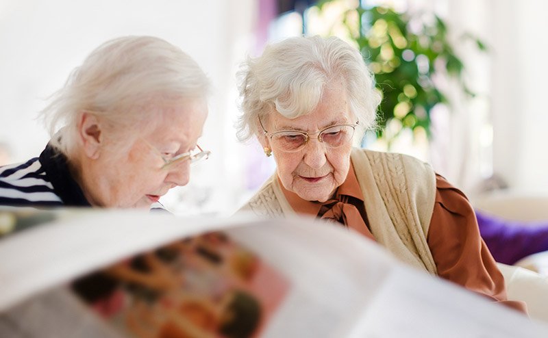 two seniors reading newspapers