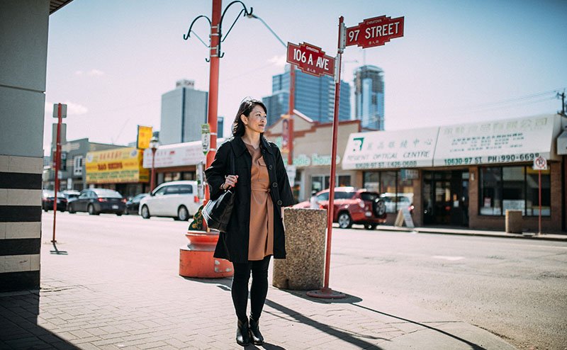 Woman walks through Edmonton's Chinatown at the corner of 97 street and 106A avenue