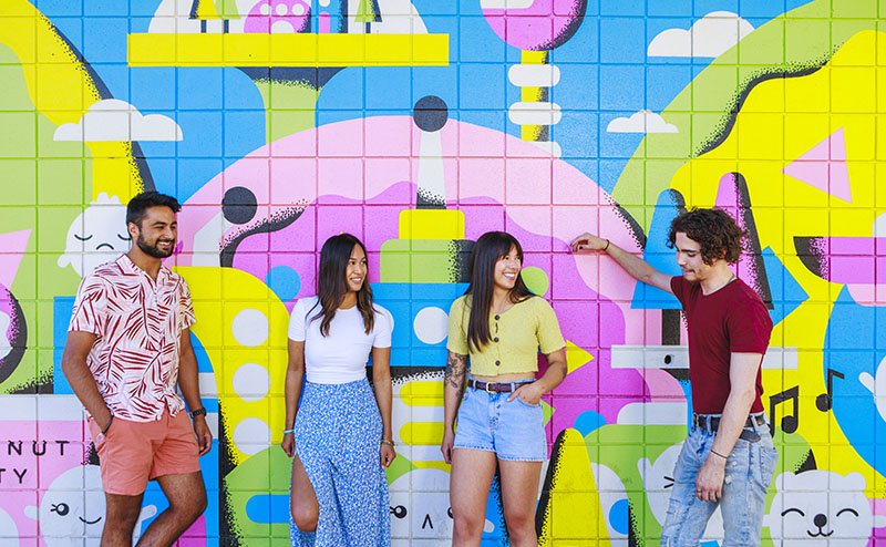 four persons standing in front of a wall mural