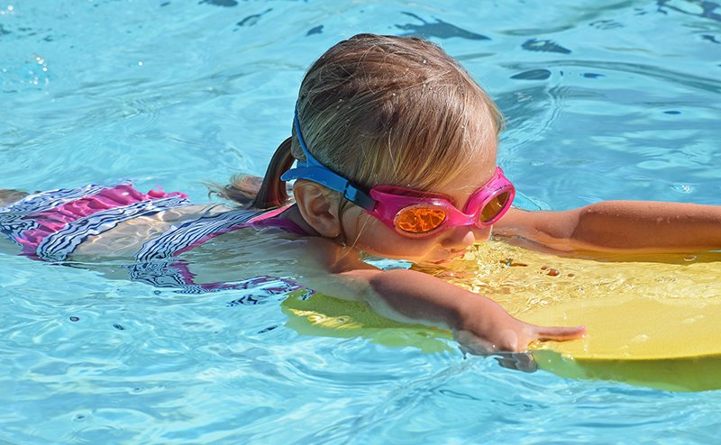 Little girl swimming at an outdoor pool